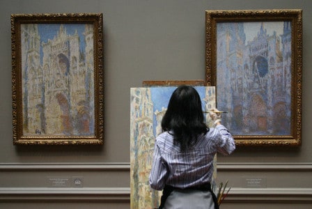 Woman with back to the camera in an Art gallery copying a painting. "Copying Monet (West Wing)" by Robin Taylor. Licensed under Creative Commons.